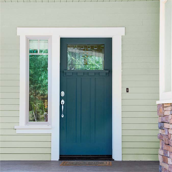 A residential home exterior in the house paint color Deep Dive, the perfect dark ocean blue paint color from Clare. Deep Dive is a dark, deep-sea inspired blue paint color that's bold and sophisticated with a hint of green undertones. Shop now.