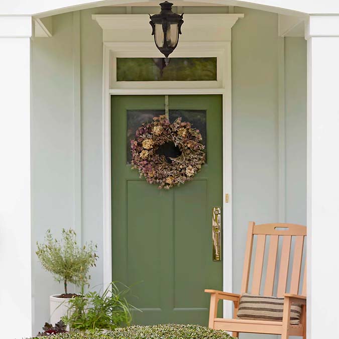 A residential home exterior in the house paint color Daily Greens, the perfect hunter green paint color from Clare. Daily Greens is the perfect hunter green paint color. Get your daily fix with this mossy olive green that’s the secret to a well-balanced space.