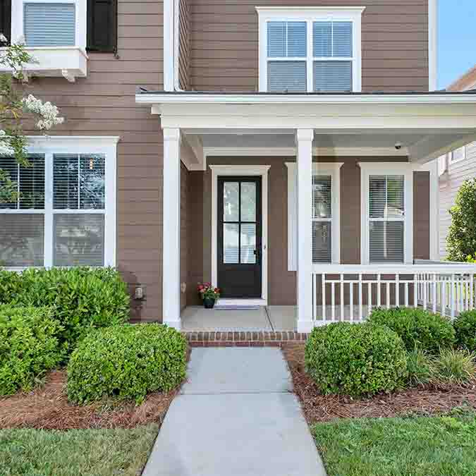 A residential home exterior in the house paint color Dirty Chai, the perfect light brown paint color from Clare. Dirty Chai is a warm, nutty light brown paint color that's the perfect pick-me-up. Just like a warm, cinnamon-y spiced chai with a shot of espresso. Shop now.