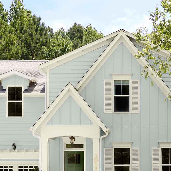 A residential home exterior in the house paint color Grayish, the perfect gray with green paint color from Clare. Grayish is a light gray paint color with obvious green undertones. Works wonders in open, airy spaces.  Shop now.