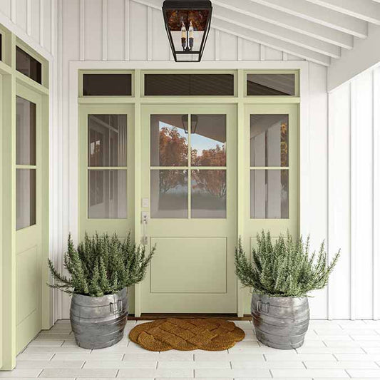 A residential home exterior in the house paint color High Vibe, the perfect green honeydew paint color from Clare. High Vibe is a luminous, light green paint glows with good energy and is the perfect choice to bring any space back into balance.
