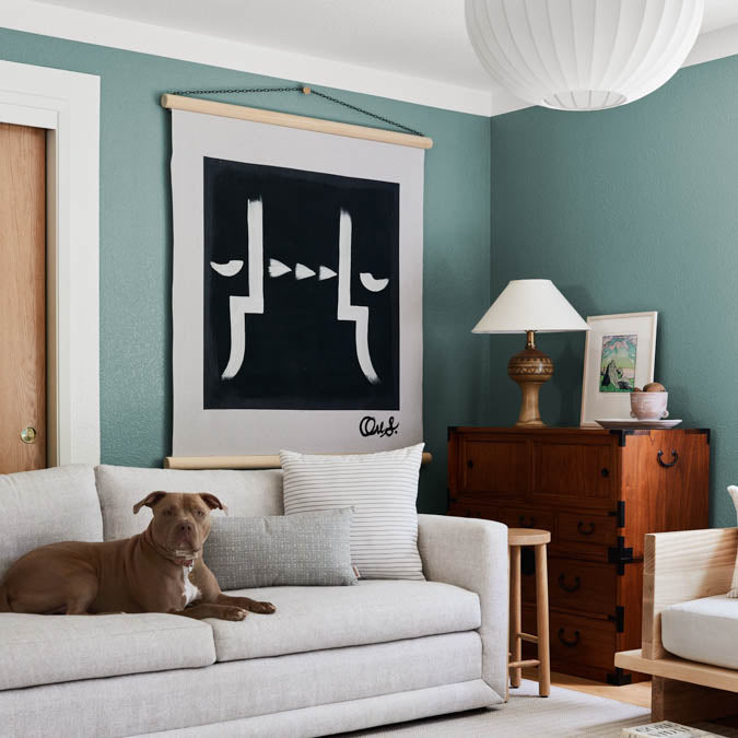 A beautiful home interior room painted in Make Waves, the perfect grayish blue-green paint color from Clare. Make Waves is a versatile greenish-blue paint color that's serene, sophisticated and nuanced, like ocean waves rippling under the sun. Shop now.